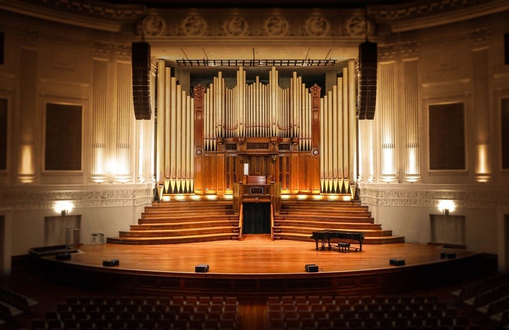 Classical concert hall with a pipe organ and a grand piano on stage