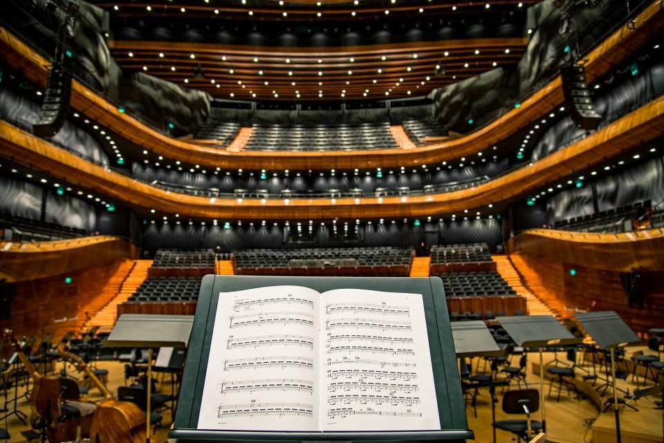 Sheet music on a stand facing the empty seats of a hall